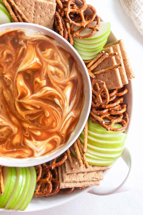 This cream cheese caramel apple dip is swirled to perfection, with homemade caramel (or store-bought) and whipped cream cheese. A perfect fruit dip with apples or graham crackers and pretzels. Great for fall, Thanksgiving, or Halloween for a sweet appetizer or dessert. Salted Caramel Cream Cheese Dip, Graham Cracker Dip Recipes, Thanksgiving Dessert Dips, Caramel Fruit Dip, Cracker Dip Recipe, Thanksgiving Dips, Fruit Dip With Cream Cheese, Cream Cheese Caramel Apple Dip, Graham Cracker Dip