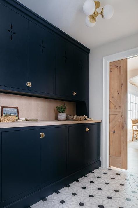 Kitchen features black flat front butlers pantry cabinets with vintage brass latch hardware, gray wash wooden countertops, black and white geometric floor tiles and a reclaimed wood pocket door. Pantry Pocket Door, Dark Blue Cabinets, Floor To Ceiling Storage, Blue Entryway, Gray Shaker Cabinets, Transitional Laundry Room, Wooden Desk Chairs, White Pantry, Latches Hardware