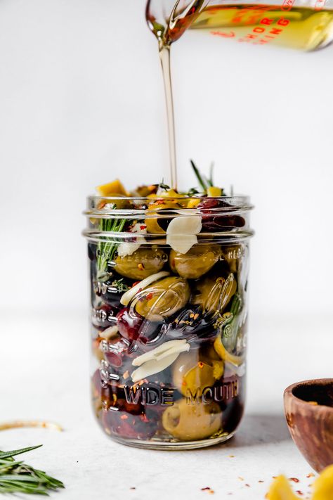 The easiest Marinated Olives recipe! A delicious blend of Italian & Greek olives marinates in olive oil infused with fresh herbs, lemon & garlic. These Italian marinated olives are perfect for everyday snacking, holiday entertaining, all of your charcuterie & cheese boards, or to offer as a showstopping hostess gift. With just 7 simple ingredients & 10 minutes of prep, making marinated olives at home couldn't be easier! #marinatedolivesrecipe #homemademarinatedolives #hostessgiftideas #... Olive Marinade, Marinated Olives Recipe, Foodiecrush Recipes, Platter Boards, Marinated Veggies, Easy Holiday Snacks, Aip Snacks, Cooking Therapy, Marinated Cheese