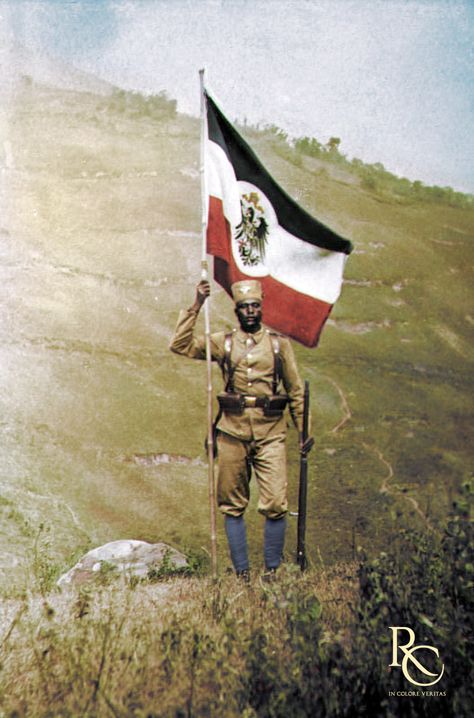 A German Schutztruppe askari poses for the camera with the German Imperial flag. German East Africa, 1906. German East Africa, Africa Flag, German Flag, Pose For The Camera, Military Photos, East Africa, Military History, Mountain Backpack, Bradley Mountain