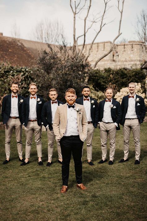 Groom in beige suit jacket and black bow tie and trousers and groomsman in light coloured trousers and orange bow ties Beige Suit Bow Tie, Light Colour Wedding Suit, Two Tone Suit Men Wedding, Two Tone Groomsmen Suits, Tan And Black Suit Wedding, Beige Suit Black Tie, Black And Beige Groomsmen, Beige And Black Groomsmen Suits, Rustic Wedding Suits For Men