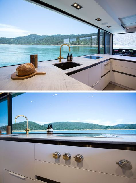 In the houseboat kitchen, a large picture window perfectly frames the views, while the cabinetry has a minimalist appearance. #Houseboat #ModernKitchen #PictureWindow Houseboat Kitchen, Boat Kitchen, Luxury Houseboats, Motorhome Interior, Boat House Interior, Houseboat Living, Lakefront Living, Alfresco Dining Area, Picture Window