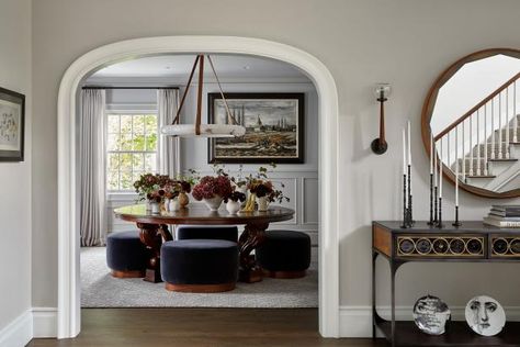 This transitional dining room is primed and ready for fall feasting. A glossy, hand-carved mahogany table, topped with jewel-toned floral arrangements, serves as the focal point of the design at the center of the room. A leather-suspended alabaster chandelier dangles overhead, while four custom-upholstered velvet navy stools provide plush seating for family and guests around the table. The moody blue upholstery complements the rich caramel tones found in the cognac leather and wood accents used Designer Nightstand, Football Rooms, Grand Kitchen, Mahogany Table, Oak Panels, Design Salon, Luxe Interiors, Interiors Design, Leather Dining Chairs