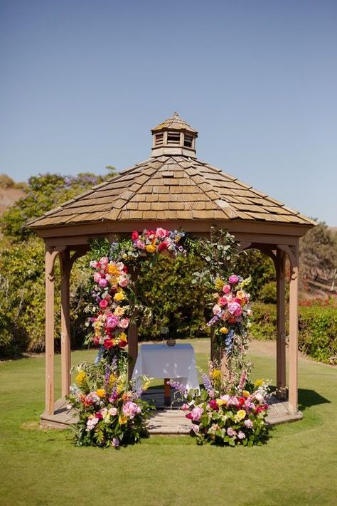 Vibrant floral arch gazebo wedding ceremony backdrop. Get inspired by this colorful Santa Barbara wedding at Glen Annie Golf Club. Captured by fine art editorial wedding photographer Morgan V Photo. Discover outdoor wedding ceremony inspo, garden wedding ideas, summer wedding color schemes and vibrant floral design ideas on the blog. Book Morgan V for your Santa Barbara California wedding at morganvphotography.com! Wedding Flowers On Gazebo, Flower Gazebo Wedding, Gazebo Floral Arrangements, Gazebo Wedding Ceremony Decorations, Round Arch Flowers, Gazebo Decorating Ideas Wedding, Wedding Gazebo Decorations Outdoor, Summer Wedding Color Schemes, Gazebo Wedding Ceremony