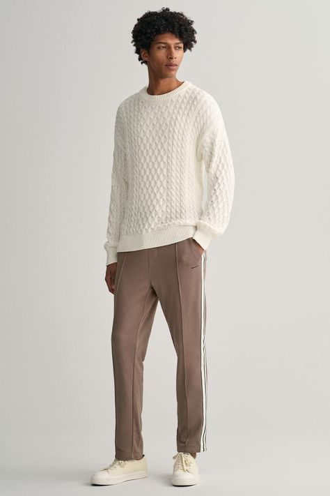 Men's brown trackpants, white cable knit sweater and off-white canvas sneakers outfit. This outfit was included in the article: How To Wear Brown Pants: 18 Outfit Examples & The Colours That Go Best, on MensFlair.com White Cable Knit Sweater Outfit Men, Cable Knit Sweater Outfit Men, White Cable Knit Sweater Outfit, Canvas Sneakers Outfit, Black Pants Outfit Men, Blue Shirt Black Pants, Cable Knit Sweater Outfit, Brown Pants Outfit, Outfit Rock