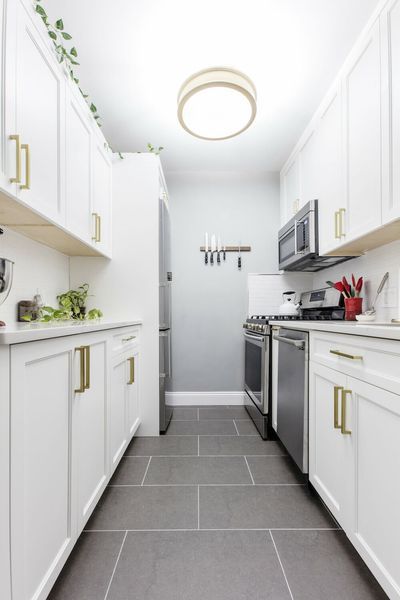 Our professional kitchen designers have helped hundreds of customers with their galley kitchen remodels. In this blog, we’ve compiled their best tips for turning a small galley kitchen into a beautiful, functional space. Read on to explore 9 clever ideas for enhancing a galley kitchen layout. White Kitchen Gray Floor, Small Kitchen Tile Floor, Galley Kitchen Colors Schemes, Galley Kitchen Backsplash, Dishwasher Bosch, Galley Kitchen Lighting, Beton Floor, White Galley Kitchens, Galley Kitchen Renovation