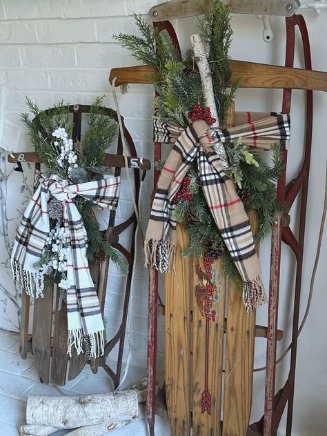 Two vintage sleds decorated with greens and a scarf. The larger one has birch logs on it. Christmas Sled Decoration Front Porches, Sleds Decorated For Christmas, Christmas Planters Outdoor, Christmas Sled Decor, Ski Lodge Aesthetic, Christmas Outdoor Decorating, Cozy Country Christmas, Christmas Sled Decoration, Christmas Sleigh Decorations