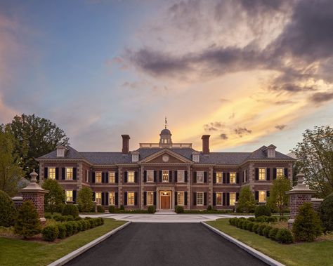 Thoughtful consideration was taken in the selection of the brick’s blend of red tones, which are complemented by the soft warm hues of the sandstone accents on this new Georgian style estate. #brickpiers #slateroof #limestonequoins #redbrickhouse #cupola #pedimentedentry #drivecourt #symmetricalarchitecture #georgianarchitecture #traditionaldesign #classicalarchitecture #sunset #newenglandestate Georgian Style Architecture, Red Brick Mansion Exterior, Brick House Mansion, Bloxburg Colonial Mansion, Brick Mansion Exterior, Red Brick Mansion, Colonial Mansion Exterior, Georgian Style Homes Exterior, Brick Georgian House