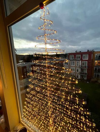 If you don't have the room for a regular Christmas tree or don't have the budget this year, then our DIY Wall Christmas Tree might be your perfect holiday solution. Obviously you can do this on a large window as well. Which is what we did! Made from firefly, or fairy lights (which are different from regular string lights) it’s pretty, space saving, inexpensive, and a real show stopper. You can use it as your main tree, or as a budget friendly way to add additional trees throughout the… Fairy Light Tree Indoor, Christmas Tree Window Lights, Fairy Light Wrapped Tree, Window Christmas Tree Ideas, Christmas Tree On Window, Christmas Tree On Wall With Lights, Christmas Tree Window Display, Christmas Lights Windows Indoor, Christmas Tree Lights On Wall