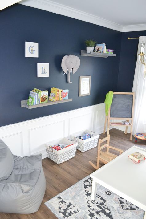 A renovated playroom featuring Goodnight Moon - a strong midnight blue paint color that's dark and alluring, like an infinite, moonlit sky. #paint #paintcolors #navy #bluepaint #playroom Blue Paint Colors For Bedroom Boys Behr, Navy Blue Chair Rail Bedroom, Navy Blue Playroom Ideas, Navy Playroom Ideas, Navy Blue Nursery Paint Color, Goodnight Moon Paint Color, Dark Blue Playroom, Boy Blue Room Ideas, Blue Boy Bedroom Ideas