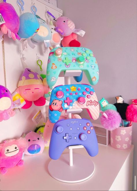 Its the little things. This is so cute for displaying all your cute controllers! #gamergirl #gamersetup #gamergirlsetup #kawaii #pastelgoth #pastelcore #pastelgamer #nintendoswitch #gamer #gamerneeds #organizedhome #kirby Xbox Setup Ideas, Kawaii Gamer Setup, Kirby Gaming Setup, Kawaii Gamer Aesthetic, Xbox Gaming Setup, Gamer Headset, Gamer Baby, Gamer Accessories, Gamer Aesthetic