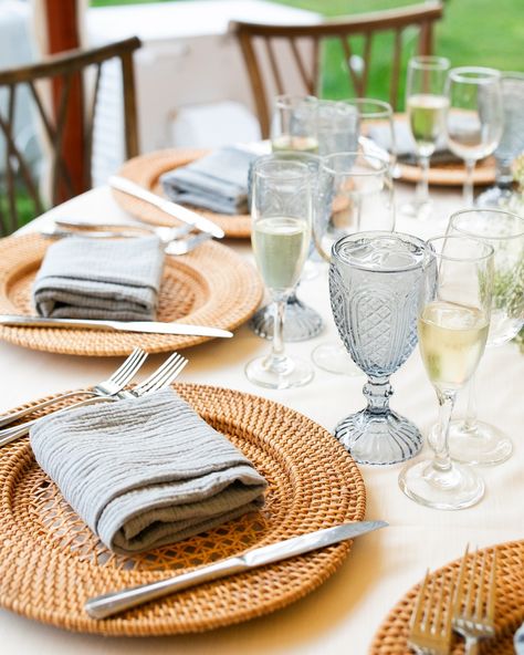 Rattan lampshades, a hint of ‘something blue’, greenery, and our Willow chairs are a stunning combination under our Sperry Tent! Dusty blue goblets, light blue napkins, and rattan chargers tied together the wedding theme for Nora + CJ’s spring wedding at Willowdale Estate. This elegant tent inspiration takes you from day to night with a warm glow from the tent lighting and colorful uplights illuminating the dance floor. Nora & CJ’s Wedding Team: Venue @willowdaleestate Photography @melanie... Woven Chargers Table Settings Wedding, Rattan Chargers Table Setting Wedding, Rattan Chargers Table Setting, Rattan Wedding, Rattan Charger Plate, Blue Goblets, Willowdale Estate, Sperry Tent, Woven Charger