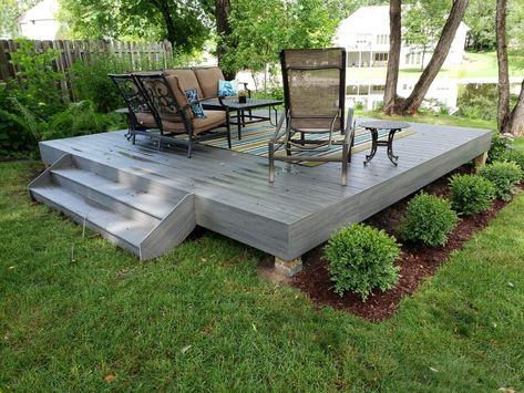 A simple ground level deck can create a nice space to entertain or relax. Add landscaping around the perimeter to finish the area and transition to the yard. Floating Deck Side Yard, Floating Deck For Pool, Uneven Ground Patio, Small Deck On Slope, Ground Level Deck Front Of House, Floating Deck Backyard, Deck In Middle Of Yard, Yard Deck Ideas Backyards, Floating Deck Landscaping Ideas