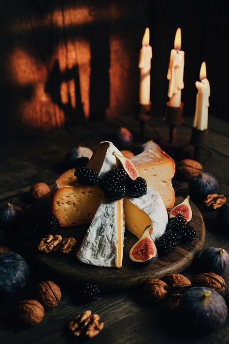 A rustic cheese board with dark wood, featuring aged cheeses, blackberries, figs, and walnuts, illuminated by candlelight with a gothic, moody ambiance. Vintage Charcuterie Board, Dark Charcuterie Board, Halloween Speakeasy, Academia Food, Cheese Board Aesthetic, Dark Academia Food, Halloween Cheese Board, Halloween Dinner Party Food, Harry Potter Dinner