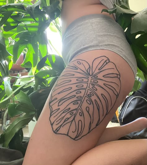 A monstera leaf thigh tattoo done in simple linework Linework Plant Tattoo, Monstera Leaf Tattoos, Monstera Tattoo Thigh, Monstera Plant Tattoo Design, Plant Tattoo Thigh, Plant Inspired Tattoos, Prayer Plant Tattoo, Plant Hip Tattoo, Green Plant Tattoo