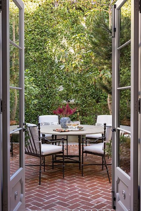 A stone top dining table sits on red brick herringbone pavers and is surround by wrought iron patio dining chairs. Red Brick Pavers Backyard, Red Brick Herringbone Patio, Checkerboard Patio, Herringbone Brick Patio, Herringbone Pavers, Red Brick Patio, Red Brick Pavers, Brick Herringbone, Stone Top Dining Table