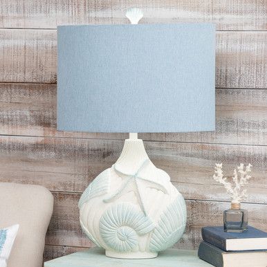 A Bella Coastal Decor Exclusive - The Marine Shell Table Lamp features a mesmerizing combination of blue, sand cream, and heathered blue hues, bringing the calming essence of the ocean into any space.Polyresin and linen20"W x 11"D x 31"HWipe with dry soft clothBlue, sand, cream and heathered blue finishUses one 100-watt max bulb Coastal Farmhouse Table, Ocean Baby Rooms, Coastal Lamps, Boho Beach Bedroom, Shell Lamps, Nautical Lamp, Mermaid Decor Bedroom, Shell Table Lamp, Surf Bedroom