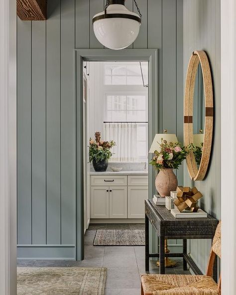 Blue shiplap trim accents a foyer boasting a black cane console table, styled and located under a round brown mirror. Cottage Paint Colors Interior, Mudroom Paint, Mudroom Paint Color, Benjamin Moore Bedroom, Entryway Colors, Entryway Paint Colors, Cottage Paint Colors, Green Grey Paint, Office Paint Colors