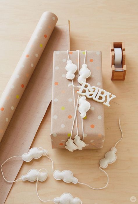 If you're headed to a baby shower, try these gift wrap ideas to really make your gift memorable. With a little DIY magic and a sweet pattern, you can perfectly wrap a baby shower gift!  Don't you just adore this plus-up to the simple polka-dotted craft paper wrap. (If you can’t bear to cut the cloud garland in two, you can always wrap it around a few more times.) The felt baby tag is a fresh and tactile finishing touch to the combo of craft paper and embroidered canvas clouds. Craft Paper Wrapping, Baby Gift Wrapping, Gift Wrap Ideas, Baby Shower Wrapping, Creative Wrapping, Gift Wrapping Ideas, Gift Wrapping Inspiration, Unique Gift Wrapping, Wrap Ideas