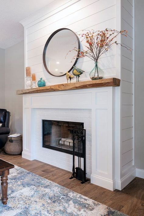 A white shiplap fireplace with warm wood accents. Styled with a round metal mirror, candles, and faux fall stems. Shiplap Fireplace Wall With Wood Mantle, Coastal Fireplace Ideas Beach, Beach Cottage Fireplace, Coastal Electric Fireplace Ideas, Coastal Fireplace Makeover, Stained Shiplap Fireplace, Tile And Shiplap Fireplace, Shiplap Over Brick Fireplace, Coastal Farmhouse Fireplace