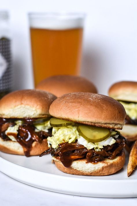 A white plate on a white counter with BBQ mushroom sliders. Small toasted buns piled with shredded mushrooms in sauce, coleslaw, and pickles. The Front slider does not have a top bun and there is a spoon of BBQ sauce above it. There is a jar of pickles and a pint of beer in the background. Bbq Mushrooms Recipes, Mushroom Sliders, Mushroom Kabobs, Bbq Mushrooms, Bbq Oysters, Mushroom Burger Recipe, Mushroom Appetizers, Baked Mushrooms, Vegan Worcestershire Sauce