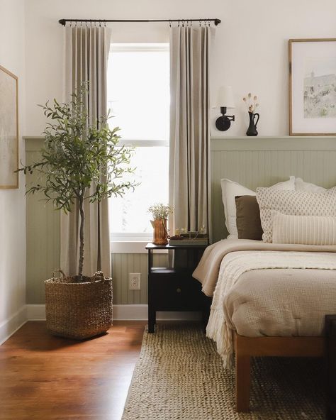 I wish this were my dreamy cottage bedroom. The color palatte is so beautiful, and all the natural materials in the room make it feel so grounded. The most impactful part of this room is the accent wall with the pale sage green wainscoting. This adds some color and life to the room and acts as a headboard substitute for the bed and a hidden shelf for extra dÃ©cor items. Cottage Bedroom Wainscoting, Sage Green Headboard Bedroom, Light Sage Accent Wall, Sage Green Wainscoting Bedroom, Gray Green Wainscotting, Cream Sage Bedroom, Sage Green Natural Bedroom, Pale Green Furniture, Bedroom Light Green Accent Wall