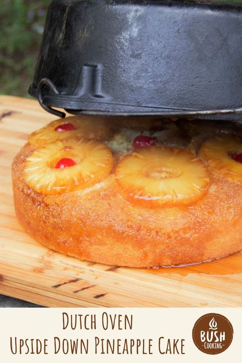 An upside-down pineapple cake on a chopping board just after being flipped with the Dutch oven still being removed. Dutch Oven Upside Down Pineapple Cake, Campfire Pineapple Upside Down Cake, Camping Pineapple Upside Down Cake, Dutch Oven Cakes, Dutch Oven Cheesecake, Easy Dutch Oven Desserts, Dutch Oven Recipes For Camping Desserts, Dutch Oven Pineapple Upside Down Cake, Dutch Oven Cake Recipes