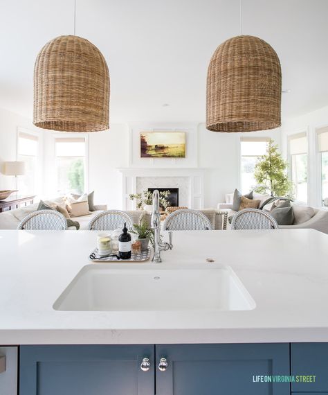 View from a kitchen island with rattan pendant lights into a living room with a Frame TV. Kitchen Lights Over Island, Lights Over Island, Beach House Lighting, Rattan Pendant Lights, Modern Coastal Home, Wicker Pendant Light, Fall Home Tour, House Lighting, Kitchen Baskets