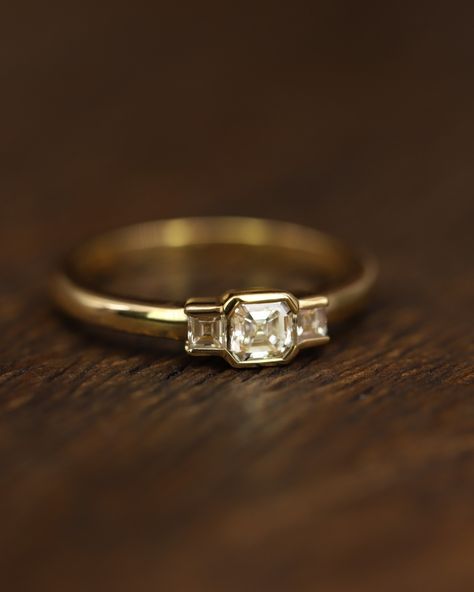 A blend of Deco inspiration and modern wearability, this exquisite ring features a stunning Asscher cut diamond elegantly flanked by two Carre cut stones on the shoulders, set in 18 carat gold. Strongly associated with the Deco period the Asscher cut diamond was first created in 1902. Asscher diamonds feature large step cut facets, producing optical properties like a ‘hall of mirrors’. With its signature clipped corners, Asscher diamonds are sometimes referred to as octagonal, or square emer... Ascher Cut Diamond Ring, Asscher Ring, Thick Band Engagement Ring, Asscher Engagement Ring, Modern Wedding Rings, The Bling Ring, Cute Engagement Rings, Asscher Diamond, Expensive Jewelry Luxury