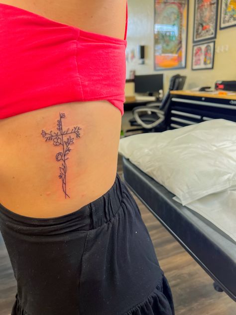 Flower With Faith Stem Tattoo, Cross With Flowers And Butterflies Tattoo, Dainty Cross With Flowers Tattoo, Flower Cross Spine Tattoo, Cross On Side Ribs, Cute God Tattoos, Flower Cross Rib Tattoo, Cute Medium Tattoos For Women, Flower Cross Tattoos For Women