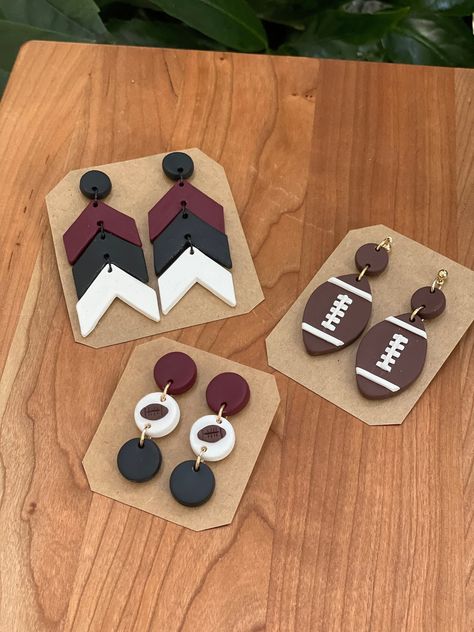 Garnet, black & white dangles. Football dangles Football Jewelry Diy, Football Craft Ideas, Clay Football Earrings, Polymer Clay Football Earrings, Football Polymer Clay Earrings, Football Clay Earrings, Sports Earrings, Football Jewelry, 2024 Jewelry