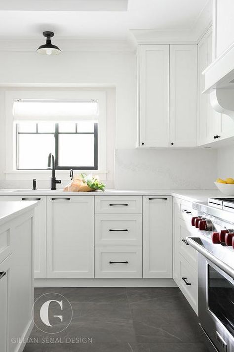 Gray tiles cover the floors of this beautiful black and white kitchen fitted with white shaker cabinets donning oil rubbed bronze hardware and a white quartz countertop holding a sink with an oil rubbed bronze gooseneck faucet beneath a black framed window dressed in a white roman shade lit by a black vintage barn flush mount light. New Kitchen Cabinets, Classic Kitchen, White Kitchen Design, Kitchen Remodeling Projects, Trendy Kitchen, Kitchen Fittings, White Kitchen Cabinets, Kitchen Remodel Idea, Black Kitchens