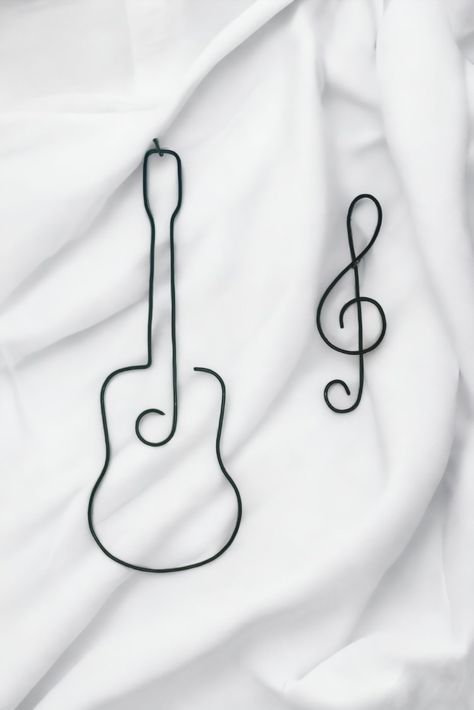 Minimalist Guitar and treble clef sign Wire Wall Hanging decor.

Elevate your home decor with our minimalist wire art guitar figurine. Crafted from a single wire, this elegant piece adds a touch of musical charm to any room. Hang it on your wall and let the harmonious vibes resonate throughout your space. Perfect for music enthusiasts and art lovers alike. Wire Music Note, Simple Wire Art, Wire Art Easy, Jurasic Word, Musical Decor, Art Guitar, Wire Sign, Wire Knitting, Solder Wire