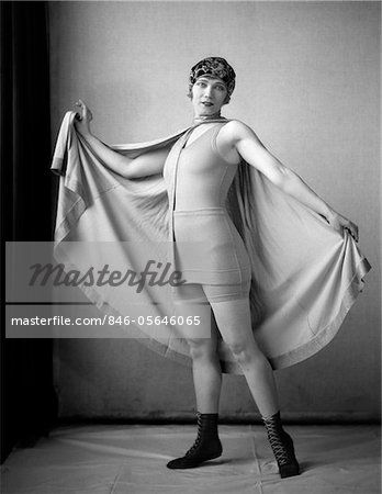 1920s WOMAN IN OLD-FASHIONED BATHING SUIT & CAP HOLDING OUT LARGE CAPE TIED AROUND NECK LOOKING AT CAMERA Holding Fabric Reference, Holding Cape Reference, Person With Cape Reference, Cape Action Pose, Cape Pose Reference, Billowing Cape Reference, Cape Reference, 1920s Bathing Suits, Vintage Fitted Cape Outerwear