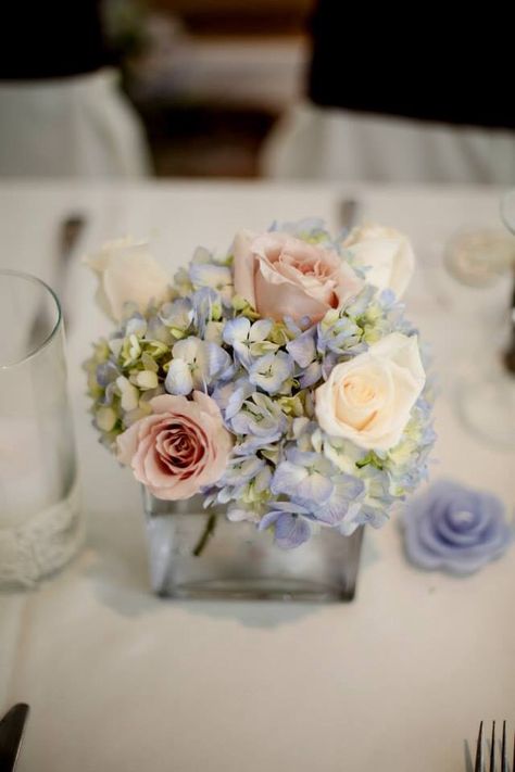 Small wedding centerpieces. Blue hydrangea and pale pink roses Hydrangea And Pink Rose Centerpiece, Pink And Blue Flower Centerpieces, Hydrangea Centerpiece Wedding Elegant, Small Flower Centerpieces Birthday, Peonies And Hydrangeas Centerpieces, Wedding Flower Arrangements Hydrangea, Small Blue And White Floral Centerpieces, Small Table Centerpiece Wedding, Small Hydrangea Arrangements