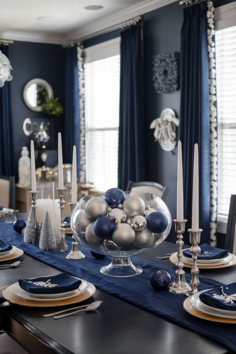 A navy blue dining room decorated for Christmas with silver accents and a bowl of ornaments as the centerpiece. Blue And White Xmas Table Decor, Christmas Table Blue And Silver, Blue Christmas Kitchen Decor, Blue And White Christmas Table Decor, Winter Tablescape Ideas, Navy Dining Room Decor, Modern Christmas Table Decor, Blue Christmas Table Decor, Blue And White Christmas Table