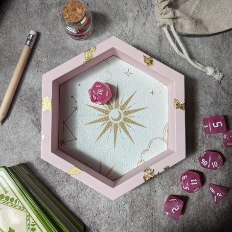 If you're looking to level up your dice rolling, swipe to take a look at some cute hexagon dice trays dropping tomorrow ✨ 24th June at 6pm ✨ All handmade from Jesmonite so they feel like stone and look amazing on your gaming table. ✨ Pink and gold celestial 🌌 Purple galaxy 🧚‍♀️ Iridescent fairy dragon scales 👻 Cute floral ghosty gals 🔮Pastel witch potions and pumpkins This is just the hex trays, a couple of other larger designs will be going live too for D&D, Pathfinder or whichever dice... D&d Dice Tray, Dice Decor, Dice Display, Witch Potions, Iridescent Fairy, Pastel Witch, Witch Potion, Imaginary Friends, Purple Galaxy