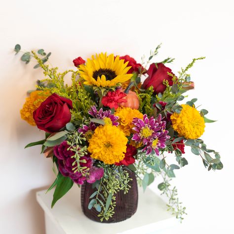 FALL in love with this charming floral arrangement. With beautiful Fall blooms and a touch of whimsy, this arrangement will add a playful touch to any space. Perfect for date nights, cozy evenings at home, or just surprising someone you love. Order now and FALL for its charm! Flower availability changes seasonally. Substitutions may apply. We promise your arrangement will be fresh and beautiful! Vase is subject to change Fall Flower Arrangements Centerpieces, Purple Fall Flowers, Fall Vase Arrangements, Fall Bouquet Flowers, Fall Wedding Flower Arrangements, Thanksgiving Flower Centerpieces, Autumn Flower Arrangements, Thanksgiving Bouquet, Autumn Floral Arrangements