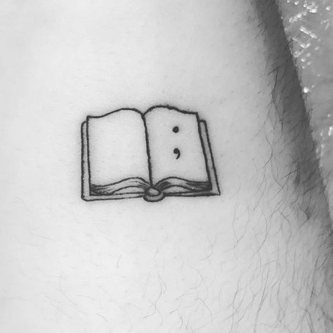 Tiny Book Tattoo Minimalist, Book Semicolon Tattoo, Writer Tattoos For Women, Minimal Book Tattoo Ideas, Tattoo Ideas For Readers, Single Line Book Tattoo, Book Tattoos Minimalist, Minimal Book Tattoo, Simple Line Book Tattoo