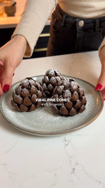 Georgina Thomas on Instagram: "Viral brownies pine cones! I had to jump on this trend and make the famous pine cones but with a gooey brownie centre using my brownies recipe. If you have any leftover brownies then this is such a cute idea for the holidays ✨🤎 Ingredients 9 brownies (see recipe on my page) Chocolate curl cereal 1-2 tbsp icing sugar Instructions 1. Make brownies (use my recipe on my profile- 2 posts down) or buy brownies! 2. Squeeze them together to form a pine cone shape. Around 9 brownies should make 6 cones. 3. Use as much cereal as you need to surround the brownie pine cones. This takes a while so be persistent! 4. Sieve with icing sugar and enjoy! #pinecones #pine #viral #chocolatebrownies #brownies #christmas #christmasdessert #holidays" Brownie Pinecone Recipe, Brownie Pine Cones With Almonds, Pine One Brownie, Brownie Pine Cones, Chocolate Pinecones Recipes, Leftover Brownies Ideas, Pine Cone Brownies, Pinecone Dessert, Brownie Pinecones