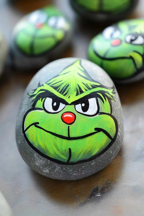 Colorful painted rock depicting the Grinch with a Santa hat, surrounded by festive decorations. What Paint To Use On Rocks, Grinch Rocks Painted, Christmas Rock Painting Ideas Easy, Grinch Designs, Christmas Rock Painting Ideas, Christmas Painted Rocks, Christmas Rock Painting, Stone Paintings, Christmas Rocks