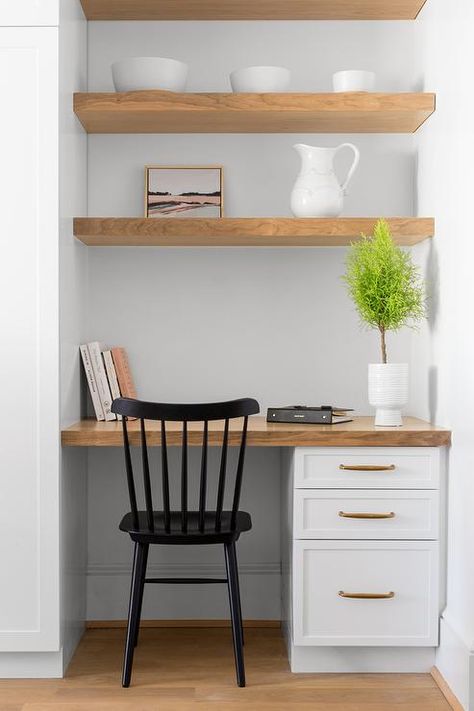 Stacked, floating wooden shelves are mounted to a white wall above a kitchen nook fitted with a two-tone desk boasting white drawers with copper pulls and a wood countertops eating a black Windsor chair. Brown Countertops, Kitchen Desk Areas, Closet Desk, Desk Nook, Home Office Closet, Brown Floor, Kitchen Desks, Cabinets White, Office Nook