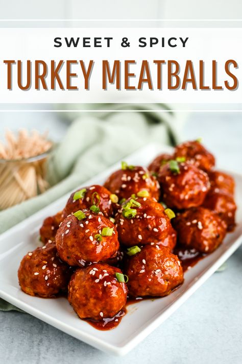 The image is a graphic that reads "Sweet and Spicy Turkey Meatballs" at the top, with an image of glazed, saucy meatballs on a white serving platter. In the background, there is a small container of toothpicks for eating at a potluck or party Turkey Meatballs Spicy, Turkey Meatballs Appetizer Party Appetizers, Sweet And Spicy Turkey Meatballs, Sweet And Spicy Chicken Meatballs, Sweet Turkey Meatballs, Turkey Meatball Appetizer Recipes, Turkey Meatball Appetizer, Sweet Chili Turkey Meatballs, Glazed Turkey Meatballs