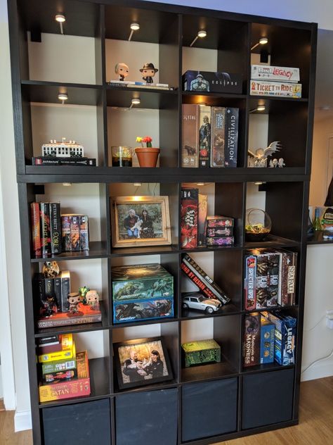 Our board game display! Two Ikea Kallax (one 4x4 with bins and one 2x4) units. We joined them together, anchored them to the wall, and added lights to each cube. We use the bins (need to dust) for our DnD gear. Table next. Board Games Storage Living Room, Board Games Living Room, Office And Board Game Room, Game Bookshelf, Board Game Display Storage, Ikea Kallax Light, Board Game Living Room, Small Board Game Room, Kallax Gaming Room