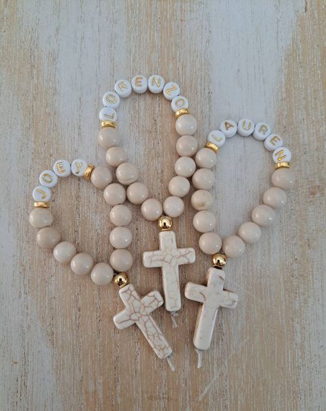 These handmade mini rosaries are perfect as a gift to yourself, teacher appreciation gift, Christmas gift for mom or godmother.  You can also purchase them in bulk for  Baptisms first communion  confirmation religious graduation gifts weddings loving memory gifts These rosaries feature 10 8mm smooth round cream fossil jasper beads nylon thread 1 20mm x30mm cream howlite cross gold metal tone accents 7mm acrylic letter beads If you would like to order a different qty than shown or a different gemstone please message me and I will reply shortly,  together we can create something perfect for you! Please include names needed and quantity in personalization box NOTE: Within Canada your order will be sent tracked packet and expedited, if you order only 1 rosary or less than 5, your order will be Mini Gifts, Gift Beaded Rosary, Personalized Rosary With Round Beads As Gift, Rosary Favors, Mini Rosary Souvenir, Cross Favors, Recuerdos Primera Comunion Ideas, Mini Rosaries, Boys First Communion