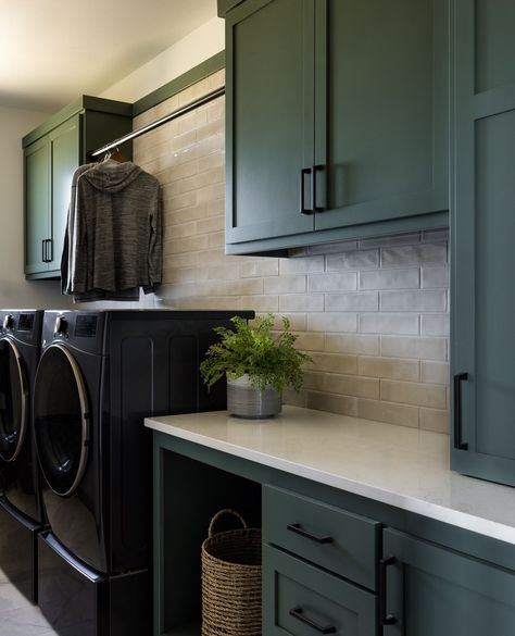 When a simple laundry room design just won't do! We treat every space in our homes the same as if they were seen all day, or just during laundry day. We believe every space in the home deserves to be just as beautiful as the next.⁠ ⁠ With a slim, textured subway tile and dark green cabinets with crisp black hardware topped with a sleek quartz countertop - our Wesport Beach House laundry room is ready for the fanciest of laundry days! ⁠ ⁠ 📸 @mirandaestes⁠ Laundry Colour Schemes, Laundry Green Cabinets, Laundry Room Ideas Green Cabinets, Green And Black Laundry Room, Green Cabinets In Laundry Room, Dark Green Laundry Room Cabinets, Laundry Room With Green Cabinets, Dark Green Cabinets Laundry Room, Sage Green Laundry Room Cabinets