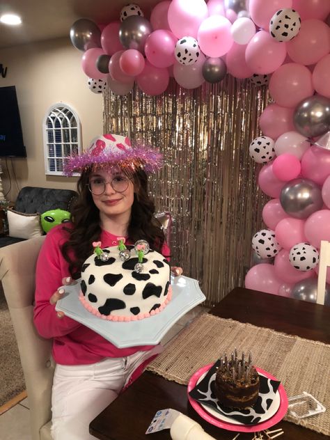 pink, cow print, silver and white balloon arch with teenage girl holding a cow print cake with aliens on it in cowbou hats. Cosmic Cowgirl Birthday Party, Space Cowgirl Sweet 16 Party, Space Cowgirl 21st Birthday, Cowgirls And Aliens Party, Space Cowgirl Party Decorations, Alien Party, Space Cowgirl, Cowgirl Birthday, Birthday Theme