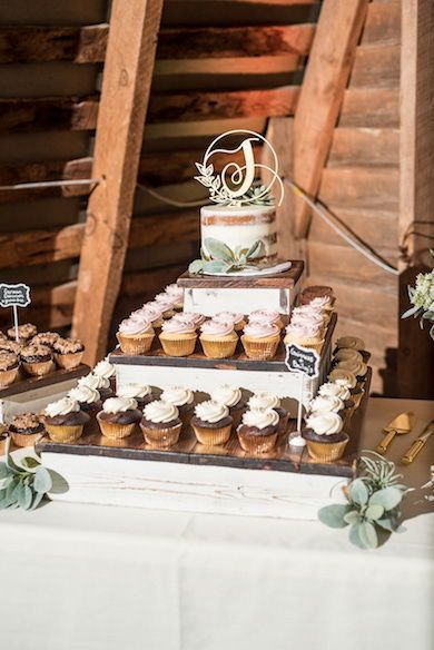 A rustic cupcake wedding cake with soft greenery and a personalized cake topper were the perfect fit for this wedding at the authentic dairy barn at 48 Fields in Leesburg, Virginia. #cupcakeweddingcake #weddingcake #weddingdessert #rusticwedding #barnwedding #countrywedding Rustic Cake With Cupcakes, One Tier Cake With Cupcakes, Rustic Cake And Cupcakes, Rustic Cake And Cupcake Display, Western Wedding Cupcake Ideas, Boho Wedding Cupcake Display, Wedding Cake Cupcake Display, Small Cake And Cupcakes Wedding, Rustic Cupcakes Wedding