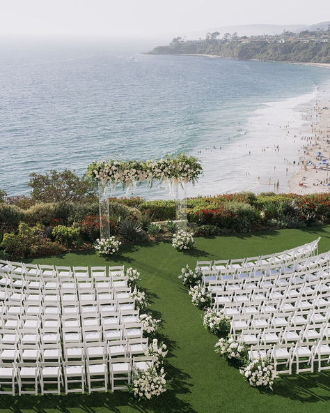 Say "I do" with the ocean as your backdrop in this breathtaking beachside wedding ceremony setup. With lush greenery, elegant white chairs, and a beautifully adorned floral arch, this setting offers the perfect combination of natural beauty and refined elegance. Ideal for couples looking to tie the knot in a serene and picturesque location by the White Chairs Wedding, Summer Wedding Venues, Ritz Carlton Laguna Niguel, Wedding Ceremony Setup, Natural Wedding Decor, Wedding Altar, Altar Ideas, Oceanfront Wedding, Beachside Wedding