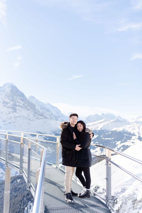 Grindelwald is a magical town in Switzerland in the Bernese Oberland region. It has an extra special charm though in the winter months, when the mountains and trees are covered with fresh snow. Click to see more from this amazing engagement photoshoot in the Swiss alps Switzerland Couple Photos, Switzerland Photoshoot Couple, Switzerland Family Photos, Mount Titlis Switzerland Photo Ideas, Mt Titlis Switzerland Outfit, Couple In Switzerland, Couple Switzerland, Switzerland Poses, Switzerland Photoshoot